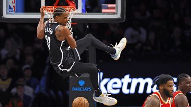 Nic Claxton, pívot de los Nets de Brooklyn, se cuelga del aro tras realizar una volcada ante los Hawks de Atlanta, el sábado 2 de marzo de 2024 (AP Foto/Noah K. Murray)