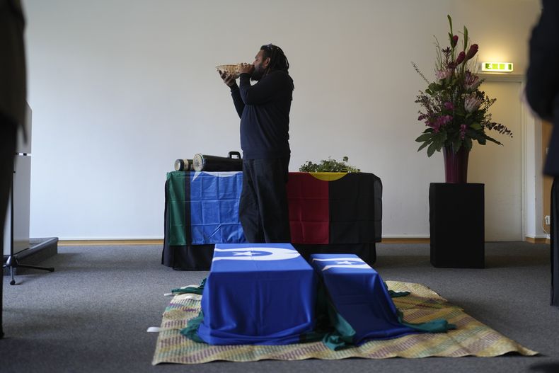Yessie Mosby, de la isla Ugar en Australia, toca un caracol detrás de varios ataúdes en una ceremonia por el regreso de ancestros aborígenes australianos a sus familiares y sus comunidades en el Museo Etnológico en Berlín, Alemania, el jueves 5 de diciembre de 2024. (AP Foto/Markus Schreiber)