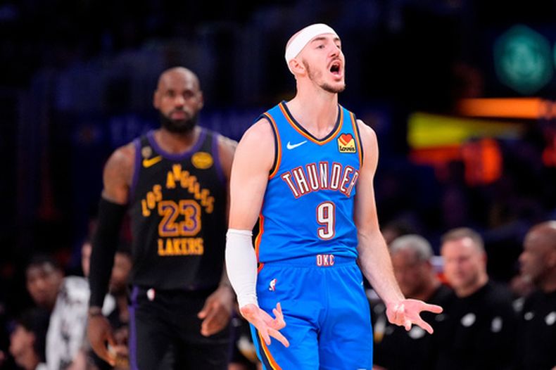 Alex Caruso (9) del Thunder de Oklahoma City, celebra después de encestar mientras en el fondo observa LeBron James, durante la primera mitad del cuarto juego de la serie segunda ronda de los playoffs del baloncesto de la NBA, el lunes 11 de mayo de 2026, en Los Ángeles. (AP Foto/Mark J. Terrill)