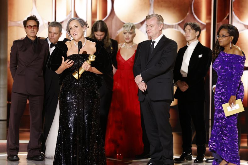 En esta imagen proporcionada por CBS, la producotra Emma Thomas, frente a la izquierda, recibe el premio a mejor película dramática por Oppenheimer acompañada por miembros del elenco y el equipo de producción incluyendo a Robert Downey Jr., de izquierda a derecha, Matt Damon, Ludwig Göransson, Florence Pugh, el director Christopher Nolan, Cillian Murphy, mientras los ve la presentadora de la gala Oprah Winfrey en la 81a edición de los Globos de Oro el domingo 7 de enero de 2024, en el Hotel Beverly Hilton en Beverly Hills, California. (Sonja Flemming/CBS via AP)