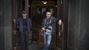 americateve | Activistas pro rusos, uno de los cuales sostiene un fusil autom&aacute;tico Kalashnikov, resguardan la entrada de un edificio del gobierno tomado en el centro de la ciudad de Luhansk, Ucrania, una de las mayores ciudades asoladas por las actividades de lo