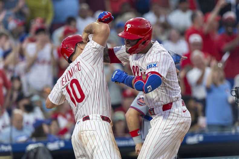 Edmundo Sosa, derecha, de los Filis de Filadelfia, celebra su cuadrangular de tres carreras con J.T. Realmuto (10) durante la cuarta entrada del juego de béisbol de Grandes Ligas frente a los Mets de Nueva York, el domingo 22 de junio de 2025, en Filadelfia. (AP Foto/Laurence Kesterson)