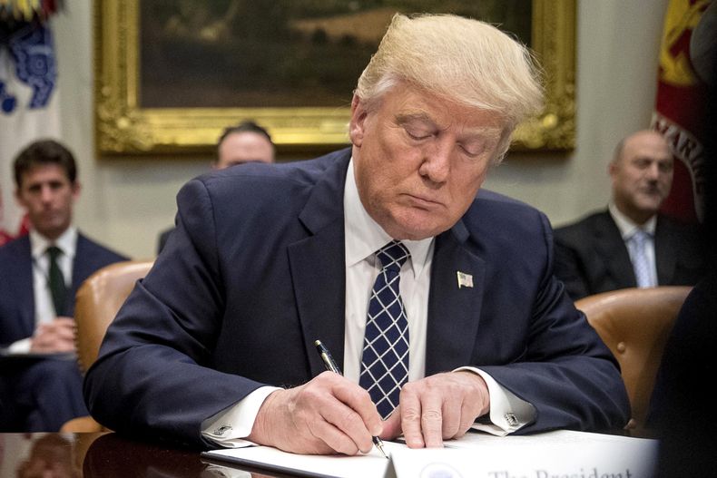 ARCHIVO - El presidente Donald Trump firma una orden ejecutiva en el Salón Roosevelt de la Casa Blanca en Washington, el 25 de abril de 2017. (AP Foto/Andrew Harnik, Archivo)