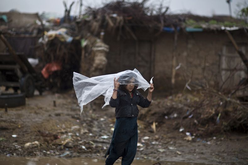 Una chica paquistan&iacute; cuya familia fue desplazada por loe enfrentamientos entre el Talib&aacute;n y el ej&eacute;rcito se cubre de la lluvia con una hoja de pl&aacute;stico en las afueras de Islamabad, Pakist&aacute;n, el martes 25 de marzo de 2014.
