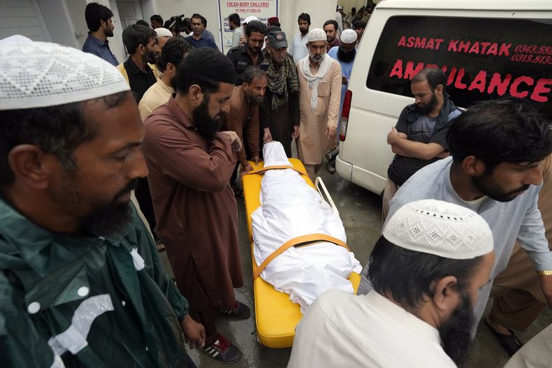 Familiares trasladan el cuerpo de un hombre fallecido tras el derrumbe de un muro debido a las lluvias del monzón en el hospital PIMS, en Islamabad, Pakistán, el 19 de julio de 2023. (AP Foto/Rahmat Gul)