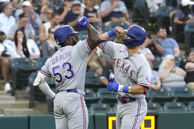 Adolis Garcia (53), de los Rangers de Texas, felicita a Josh Jung en el plato después del cuadrangular frente al abridor de los Medias Blancas de Chicago, Tanner Banks, durante la tercera entrada del juego de béisbol el lunes 19 de junio de 2023, en Chicago. (AP Foto/Charles Rex Arbogast)