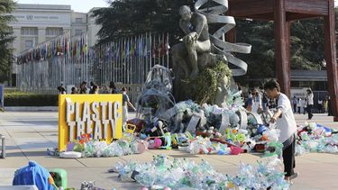 Benjamin Von Wong, a la derecha, un artista y activista canadiense, amontona pilas de desechos plásticos sobre una gran escultura que diseñó frente a la oficina de las Naciones Unidas en Ginebra, Suiza, el lunes 11 de agosto de 2025. (Foto AP/ Jennifer McDermott)