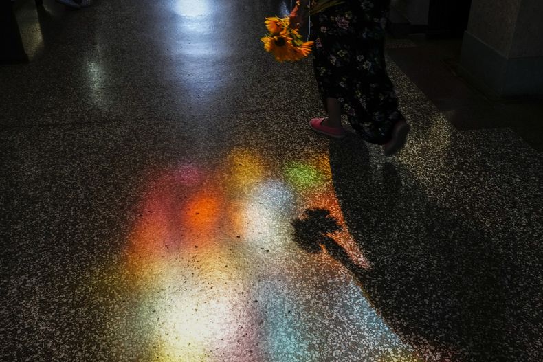 Una persona que lleva una ofrenda de flores entra al santuario de la Virgen de la Caridad del Cobre en El Cobre, Cuba, el domingo 11 de febrero de 2024. (AP Foto/Ramón Espinosa)