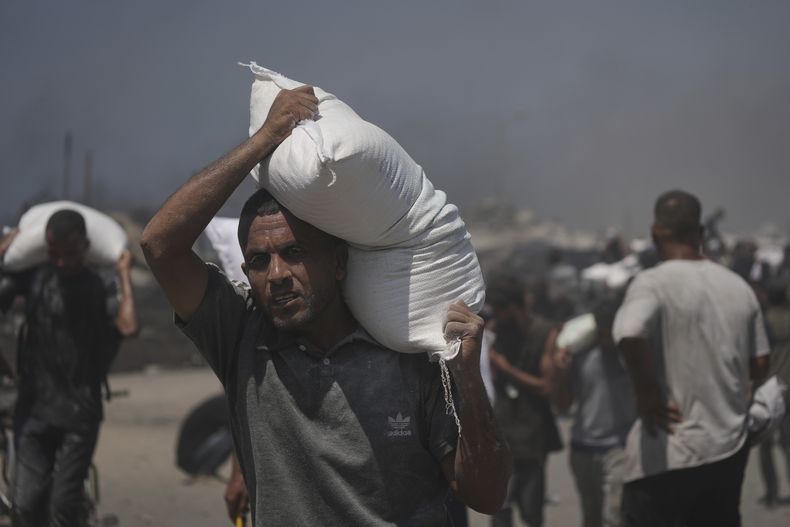 Palestinos cargan sacos de harina transportados por un convoy humanitario que llegó a Ciudad de Gaza desde el norte de la Franja de Gaza, el domingo 27 de julio de 2025. (AP Foto/Jehad Alshrafi)
