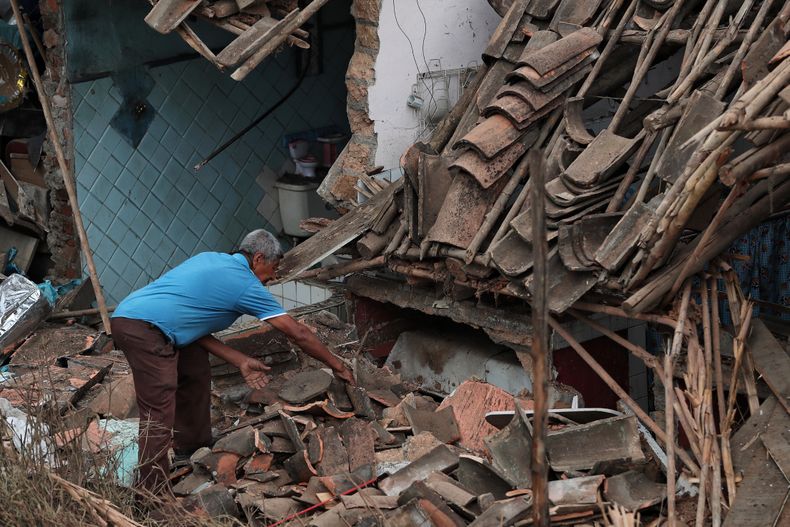 Un hombre recoge tejas rotas después de un ataque atribuido por los militares a disidentes de las desmovilizadas Fuerzas Armadas Revolucionarias de Colombia en Mondomo, Colombia, el sábado 15 de noviembre de 2025. (AP Foto/Santiago Saldarriaga)