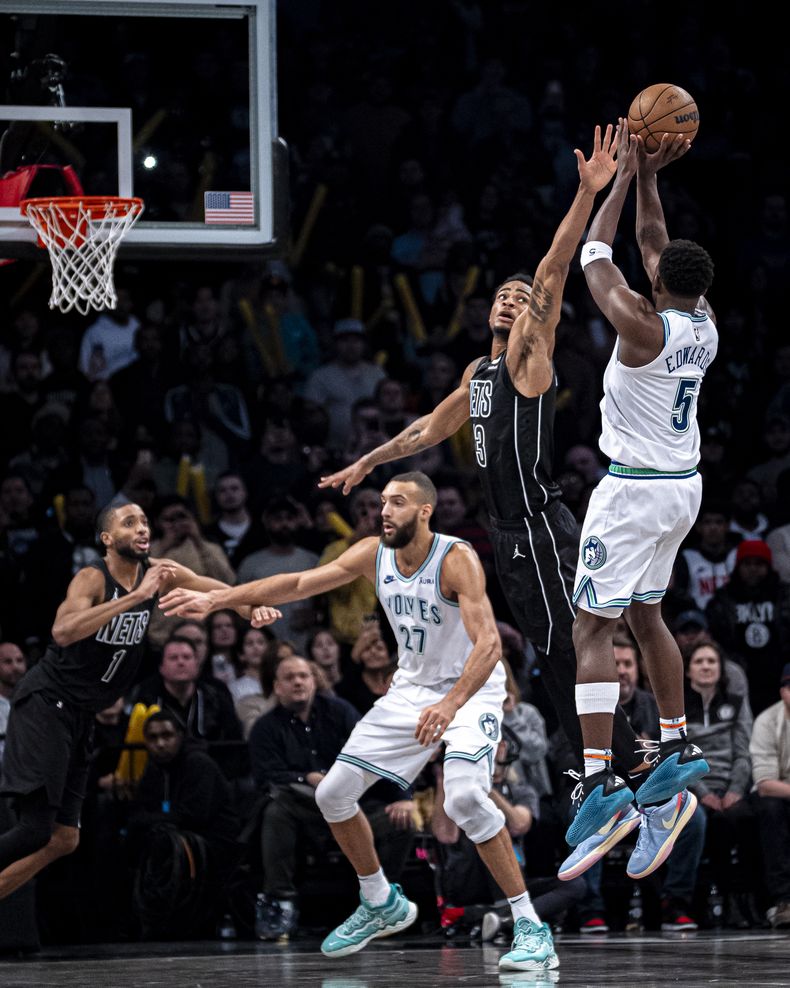 El escolta de los Timberwolves de Minnesota, Anthony Edwards (5), dispara sobre el pívot de los Nets de Brooklyn, Nic Claxton, durante la segunda mitad del partido de baloncesto de la NBA en Nueva York, el jueves 25 de enero de 2024. (AP Foto/Peter K. Afriyie)