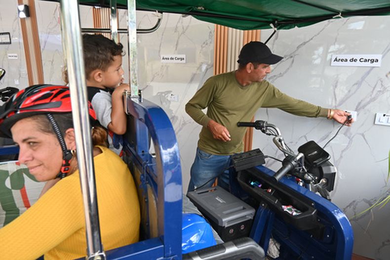 Lorenzo Ravelo, a la derecha, enchufa su triciclo eléctrico en una estación solar en Santa Clara, Cuba, el sábado 2 de mayo de 2026. (AP Foto/Jorge Luis Baños)