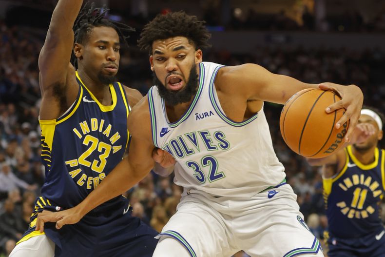 Karl-Anthony Towns, de los Timberwolves de Minnesota, conduce el balón frente a Aaron Nesmith, de los Pacers de Indiana, en el encuentro del sábado 16 de diciembre de 2023 (AP Foto/Bruce Kluckhohn)