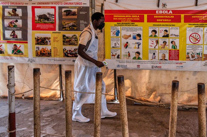Un trabajador sanitario pasa junto a carteles informativos y de advertencia sobre el ébola en una clínica provisional ubicada en el paso fronterizo de Mpondwe, que conecta Uganda con la República Democrática del Congo, el jueves 4 de junio de 2026. (Foto AP/Hajarah Nalwadda)