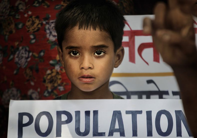 ARCHIVO - Un niño sostiene un cartel durante una manifestación en la que activistas locales reclaman un proyecto de ley de control de población que limite a dos el número de hijos por pareja, en Nueva Delhi, India, el 11 de julio de 2011. (AP Foto/Manish Swarup, archivo)