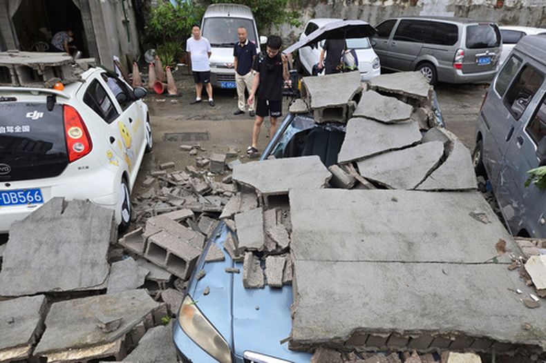 Vecinos miran autos dañados por un muro caído tras el paso del tifón Dolphin en Wenzhou, en la provincia oriental china de Zhejiang, el lunes 10 de agosto de 2026. (Chinatopix via AP)