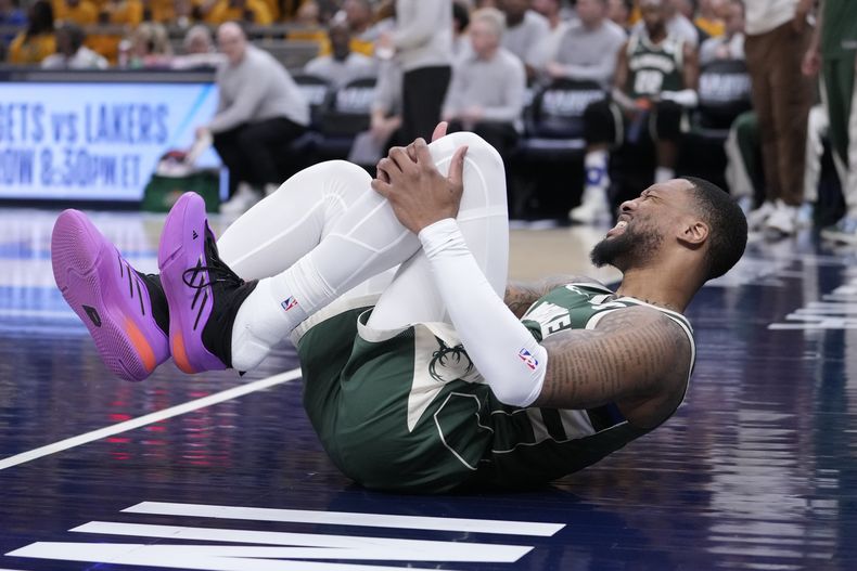 El base de los Bucks de Milwaukee Damian Lillard se toma la rodilla tras sufrir una lesión en el juego 3 de la serie de primera ronda ante los Pacers de Indiana el viernes 26 de abril del 2024. (AP Foto/Michael Conroy)