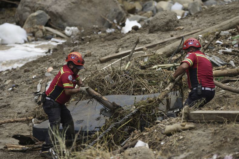 Los bomberos limpian los escombros mientras buscan sobrevivientes donde las casas fueron arrasadas por la crecida del río El Naranjo después de fuertes lluvias en las afueras de la ciudad de Guatemala, el lunes 25 de septiembre de 2023. (AP Foto/Moisés Castillo)