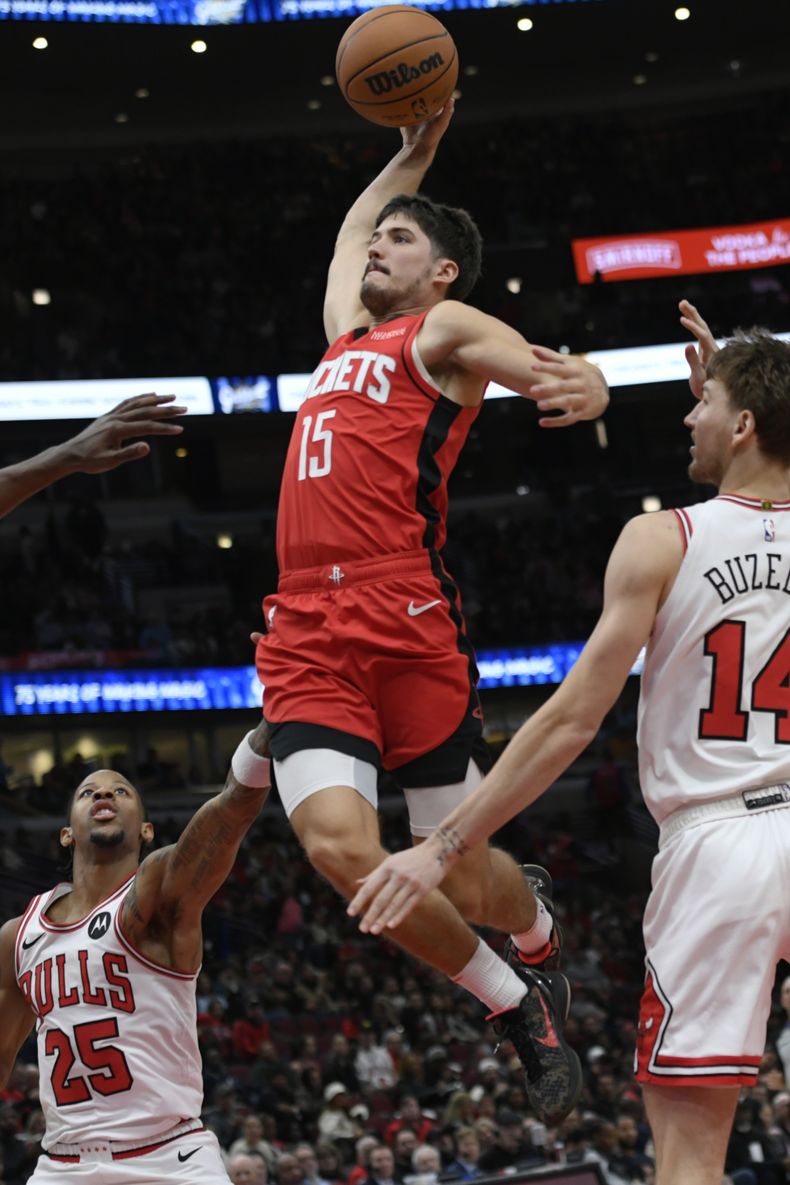 Reed Shepard (15), de los Rockets de Houston, se alza para retacar el balón en el aro ante la mirada de Matas Buzelis (14) y Dalen Terry (25), de los Bulls de Chicago, durante la segunda mitad del juego de baloncesto de la NBA, el domingo 17 de noviembre de 2024, en Chicago. (AP Foto/Paul Beaty)