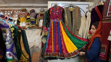 Tahmina Mangal muestra un vestido tradicional afgano en su tienda de ropa en Kabul, Afganistán, el domingo 4 de octubre de 2026. (AP Foto/Siddiqullah Alizai)