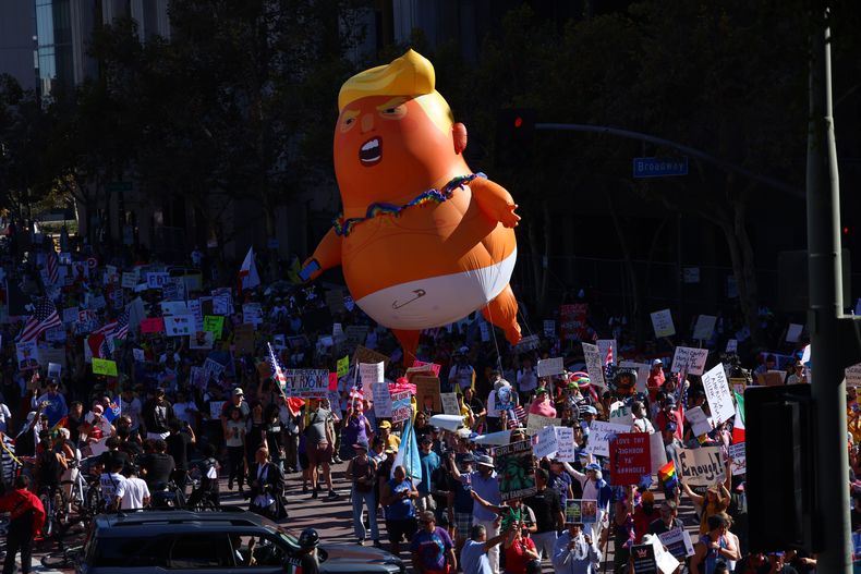 Manifestantes con un globo gigante de Donald Trump marchan durante la protesta Sin Reyes el sábado 18 de octubre de 2025, en Los Ángeles. (AP Foto/Ethan Swope)