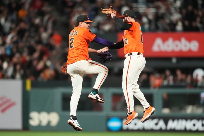 El dominicano Willy Adames (izquierda) y Casey Schmitt, de los Gigantes de San Francisco, festejan la victoria sobre los Rockies de Colorado, el viernes 26 de septiembre de 2025 (AP Foto/Jeff Chiu)