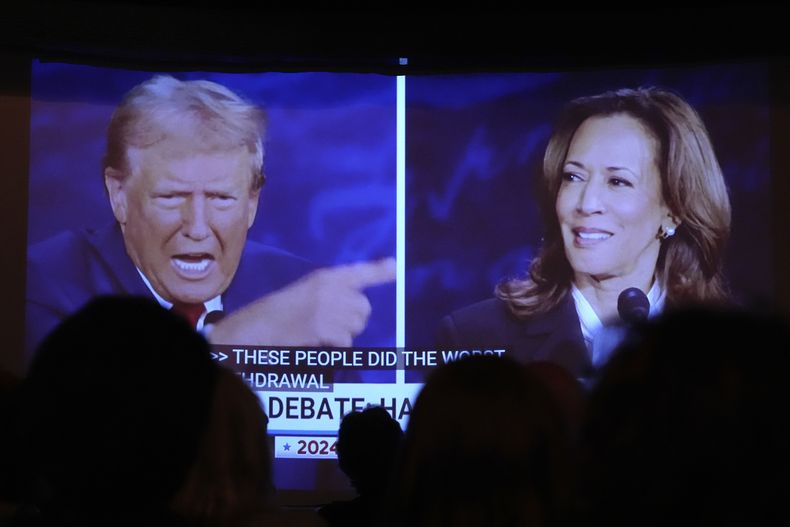 El expresidente estadounidense Donald Trump, candidato republicano a la presidencia, y la vicepresidenta Kamala Harris, aspirante demócrata la presidencia, debaten mientras varias personas los observan en una pantalla en One Longfellow Square, el martes 10 de septiembre de 2024, en Portland, Maine. (AP Foto/Robert F. Bukaty)