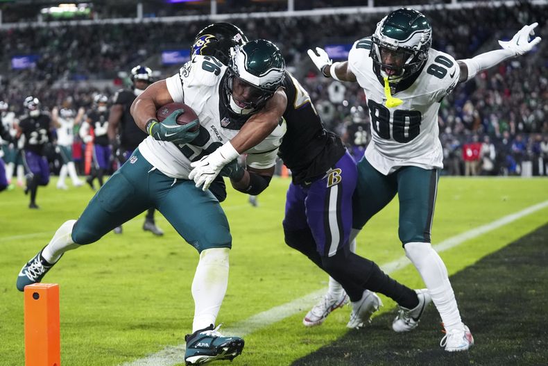 El running back Saquon Barkley, izquierda, de los Eagles de Filadelfia, es golpeado por Marlon Humphrey, centro, cornerback de los Ravens de Baltimore, mientras el wide receiver Parris Campbell (80) observa a su compañero conseguir un touchdown en la segunda mitad del partido de la NFL, el domingo 1 de diciembre de 2024, en Baltimore. (AP Foto/Stephanie Scarbrough)