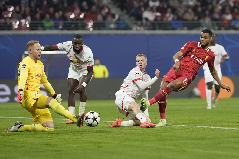 El portero del Leipzig, Peter Gulacsi, izquierda, realiza una atajada frente a Cody Gakpo (derecha) del Liverpool durante el partido de la Liga de Campeones entre el RB Leipzig y el Liverpool en el RB Arena en Leipzig, Alemania, el miércoles 23 de octubre de 2024. (Foto AP/Matthias Schrader)