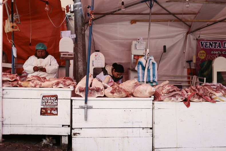 Vendedores ofrecen cerdo en un mercado en La Paz, Bolivia, el viernes 27 de diciembre de 2024. (AP Foto/Gastón Brito)