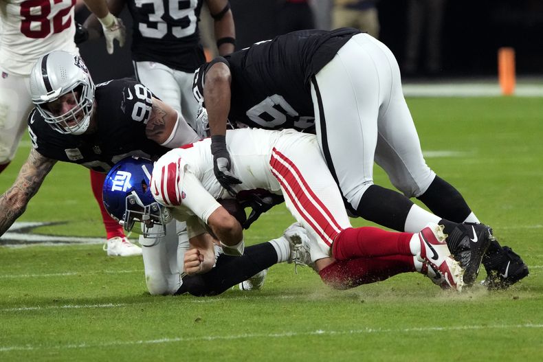 El quarterback de los Giants de Nueva York Daniel Jones capturado por el defensive end de los Raiders de Las Vegas Maxx Crosby y el tacle Adam Butler en el encuentro del domingo 5 de noviembre del 2023. (AP Foto/Rick Scuteri)