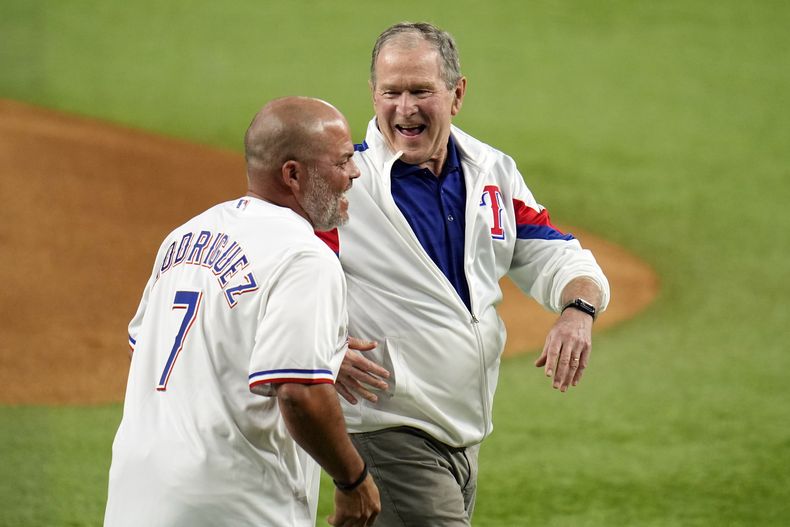 El expresidente estadounidense George W. Bush ríe con el expelotero puertorriqueño Iván Rodríguez, luego de hacer el primer lanzamiento de la Serie Mundial, el viernes 27 de octubre de 2023, en Arlington, Texas (AP Foto/Julio Cortez)