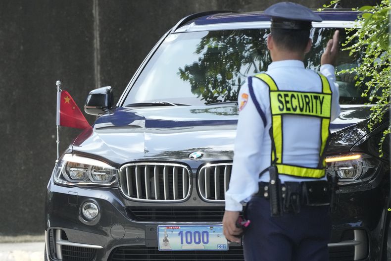 ARCHIVO - Un guardia de seguridad da indicaciones a un vehículo con placas diplomáticas y la bandera china mientras aparca en el Departamento de Asuntos Exteriores de Filipinas en Manila, Filipinas, el 7 de agosto de 2023. (AP Foto/Aaron Favila, Archivo)