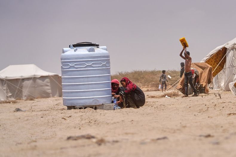 Yemeníes desplazados recogen agua en el campamento de Al-Firdaws en Ras Imran, a las afueras de Adén, Yemen, el lunes 14 de septiembre de 2026. (AP Foto/Abdulnasser Alseddik)