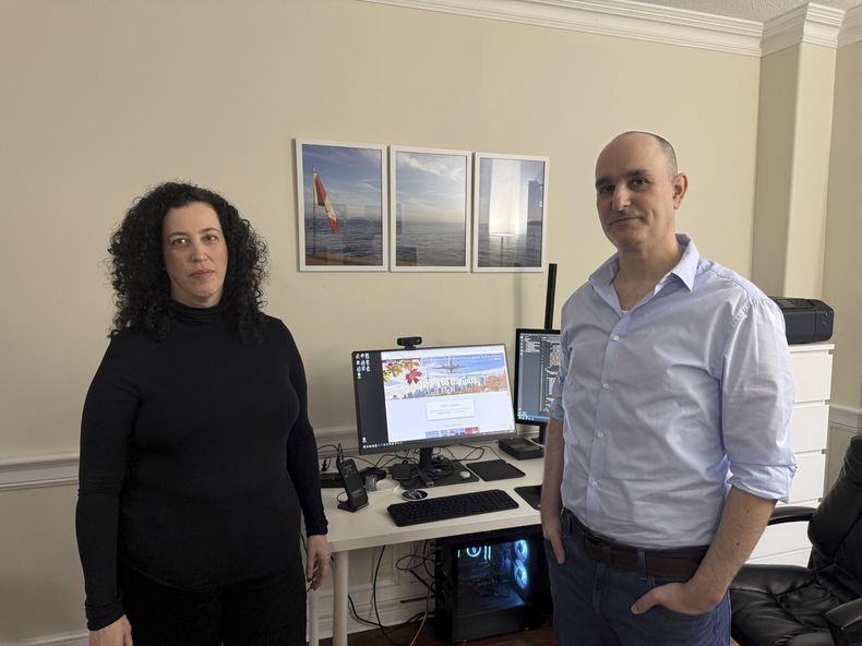 Michal Harel y su marido Avital Epstein muestran la página web que han creado para ayudar a los israelíes a trasladarse a Canadá en Oakville, Ontario, Canadá, el miércoles 4 de diciembre de 2024. (AP foto/Rob Gillies)
