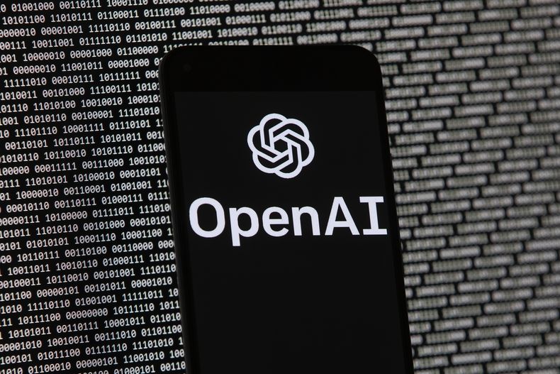 ARCHIVO - El logo de OpenAI, visto en un celular colocado delante de una pantalla con datos binarios aleatorios, el 9 de marzo de 2023, en Boston. (AP Foto/Michael Dwyer, archivo)
