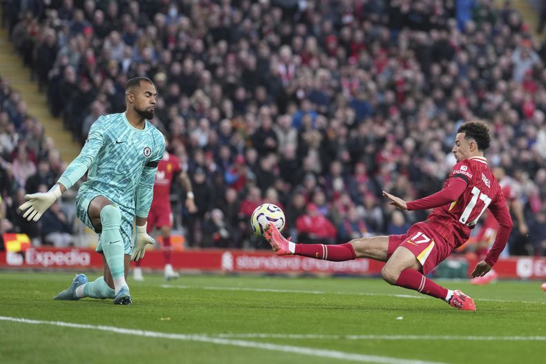 Curtis Jones (derecha) anota el segundo gol de Liverpool ante el arquero Robert Sánchez en la victoria 2-1 ante Chelsea en la Liga Premier, el domingo 20 de octubre de 2024, en Liverpool. (AP Foto/Jon Super)