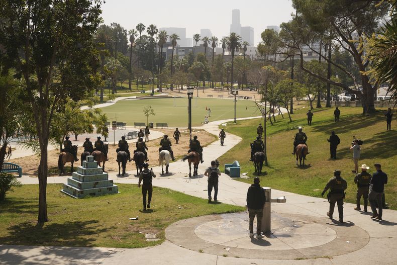 Agentes federales ingresan a caballo al Parque MacArthur, el 7 de julio de 2025, en Los Ángeles. (Foto AP/Damian Dovarganes)