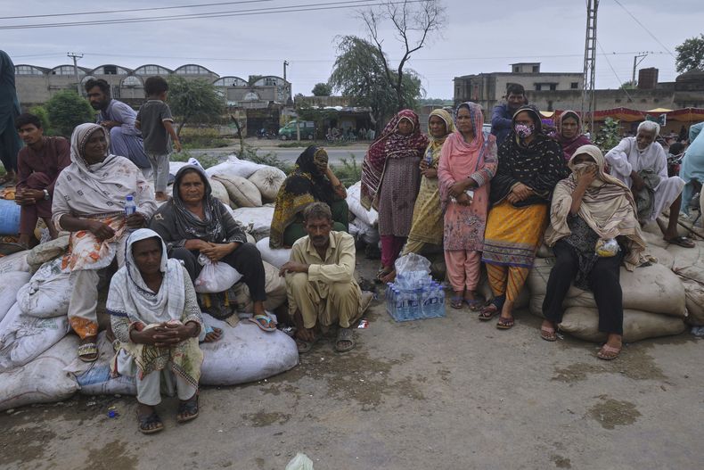 Vecinos refugiados tras ser evacuados de una zona inundada después lluvias torrenciales y un aumento del caudal de los ríos tras la liberación de agua en represas indias, en Pindi Bhattian, Pakistán, el domingo 31 de agosto de 2025. (AP Foto/A. Rizvi)