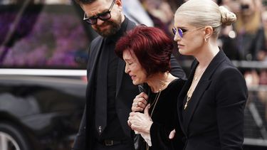 La familia de Ozzy Osbourne, de izquierda a derecha, Jack Osbourne, Sharon Osbourne y Kelly Osbourne, depositan flores y ven las flores colocadas en el banco del puente Black Sabbath en Broad Street en memoria del líder de Black Sabbath, Ozzy Osbourne, antes de la procesión fúnebre, en Birmingham, Inglaterra, el miércoles 30 de julio de 2025. (Jacob King/PA via AP)