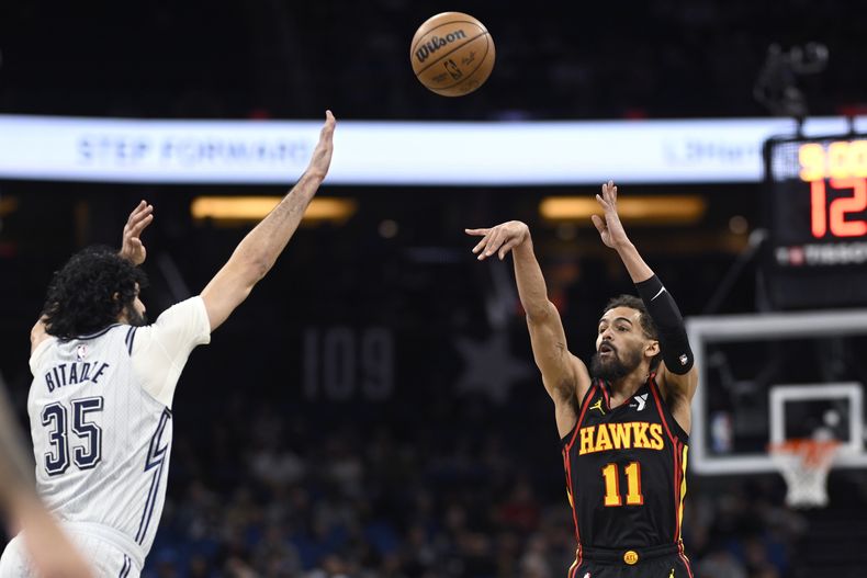El base de los Hawks de Atlanta Trae Young lanza un triple frente al pívot del Magic de Orlando Goga Bitadze en el encuentro del lunes 10 de febrero del 2025. (AP Foto/Phelan M. Ebenhack)