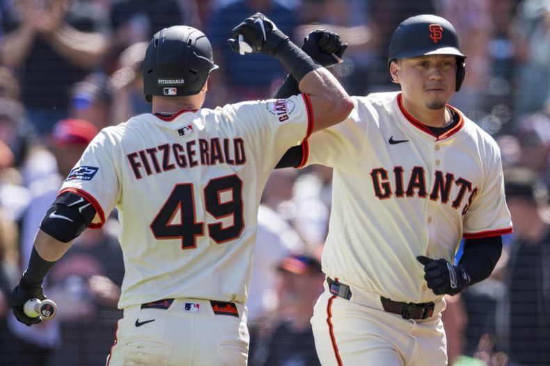 El venezolano Wilmer Flores, de los Gigantes de San Francisco, celebra su jonrón con Tyler Fitzgerald, durante el encuetnro ante los Rojos de Cincinnati, el miércoles 9 de abril de 2025 (AP Foto/Nic Coury)