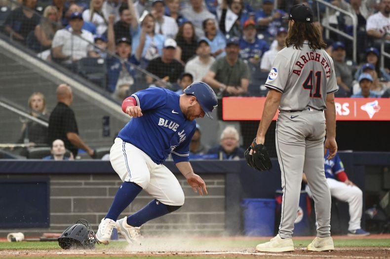 El mexicano Alejandro Kirk, de los Azulejos de Toronto, anota frente a Spencer Arrighetti, de los Astros de Houston, el martes 2 de julio de 2024 (Jon Blacker/The Canadian Press via AP)