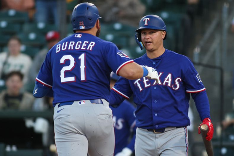 Jake Burger (21), de los Rangers de Texas, es felicitado por Joc Pederson, derecha, después de batear un cuadrangular solitario durante la tercera entrada del juego de béisbol de Grandes Ligas ante los Atléticos el lunes 13 de abril de 2026, en West Sacramento, California. (AP Foto/Scott Marshall)