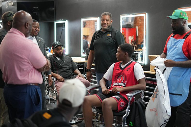 Khalil Thompson, centro y de pie, cofundador de Win With Black Men, dirige un debate en la barbería Philly Cuts de Filadelfia, el viernes 21 de agosto de 2026. (Foto AP/Matt Rourke)