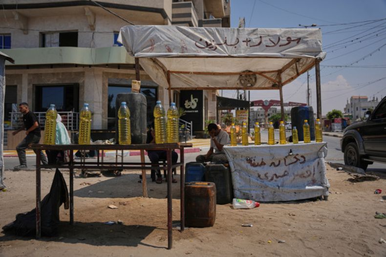 Un vendedor palestino ofrece botellas de combustible en el campo de refugiados de al-Maghazi, en el centro de la Franja de Gaza, el 15 de agosto de 2026. (AP Foto/Abdel Kareem Hana)