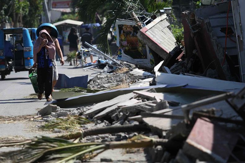 Vecinos pasan junto a escombros de un edificio dañado en General Santos, en el sur de Filipinas, el jueves 11 de junio de 2026, tras un fuerte sismo el lunes. (AP Foto/Basilio Sepe)