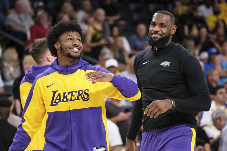 ARCHIVO - Foto del domingo 6 de octubre del 2024, el base de los Lakers de Los Ángeles Bronny James y el alero LeBron James calientan antes de un encuentro de pretemporada ante los Suns de Phoenix. (AP Foto/William Liang, Archivo)