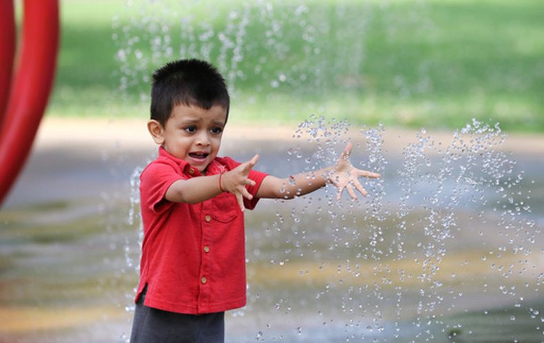 Jiyan Patel, de 2 años, extiende la mano hacia los chorritos de agua mientras juega en la fuente del Legion Park, en Owensboro, Kentucky, el lunes 6 de julio de 2026. (Alan Warren/The Messenger-Inquirer vía AP)