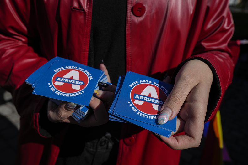 ARCHIVO - Miembros de organizaciones LGBTQ+ reparten calcomanías en apoyo a un nuevo borrador de la Constitución en Santiago, Chile, el 15 de agosto de 2022, que luego fue rechazado por los votantes en un plebiscito. Los partidos políticos presentarán un segundo proyecto de Constitución para que los electores decidan en un nuevo plebiscito el 17 de diciembre. (AP Foto/Esteban Félix, Archivo)
